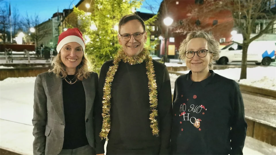 En man och två kvinnor i julglitter utomhus.