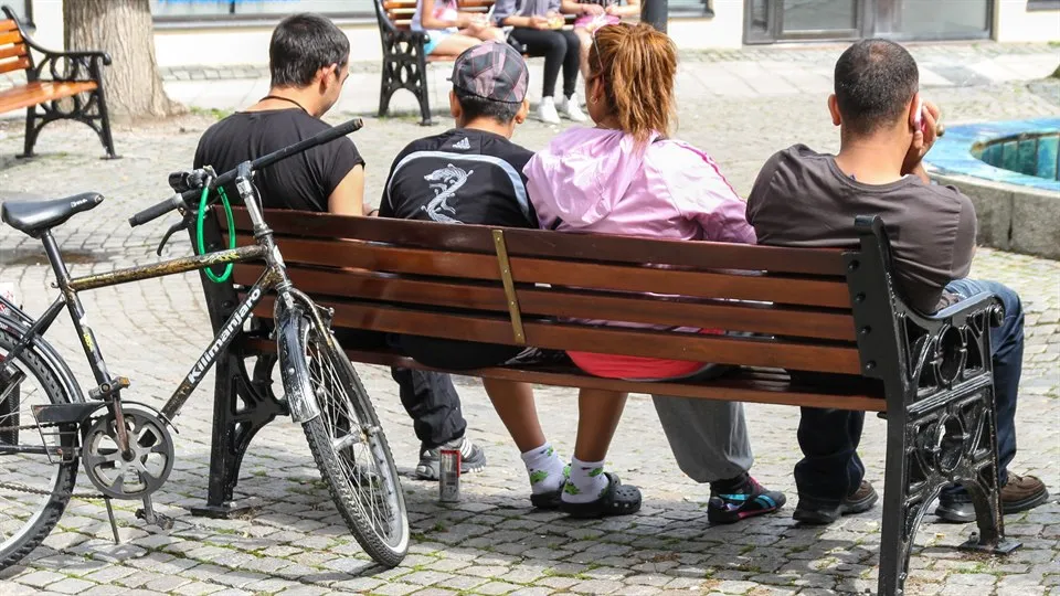 Four yougers hanging around on a square-bench 