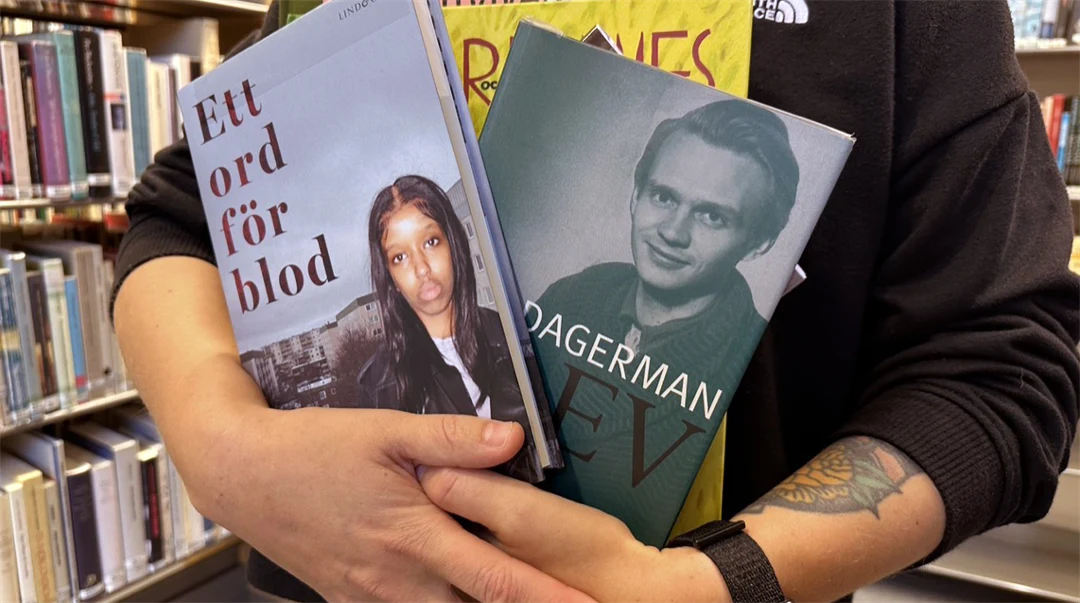 En person håller böcker i sin famn i ett bibliotek