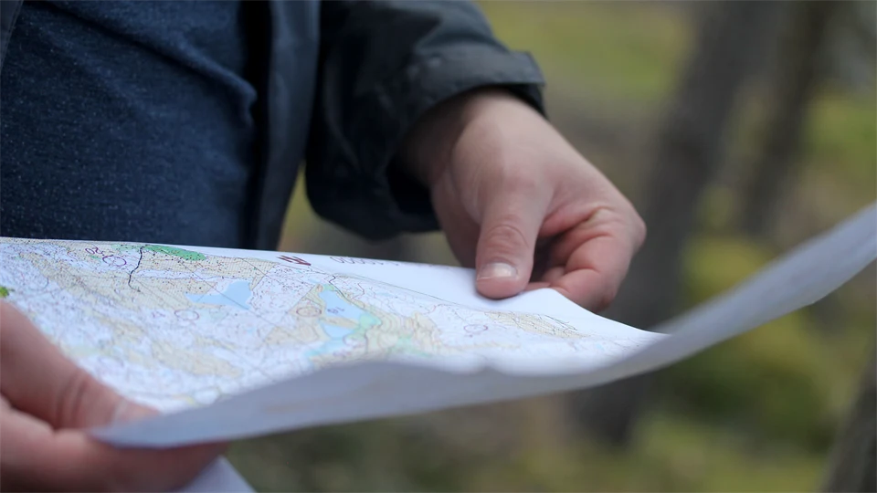 Person läser orienteringskarta med natur i bakgrunden