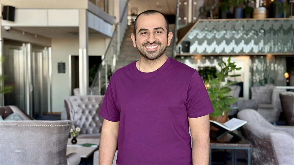 Smiling man with a buzz cut wearing a purple t-shirt.