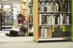 Läser bok sittande på golvet