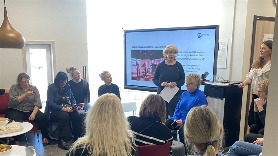 en person står framför en skärm och presenterar