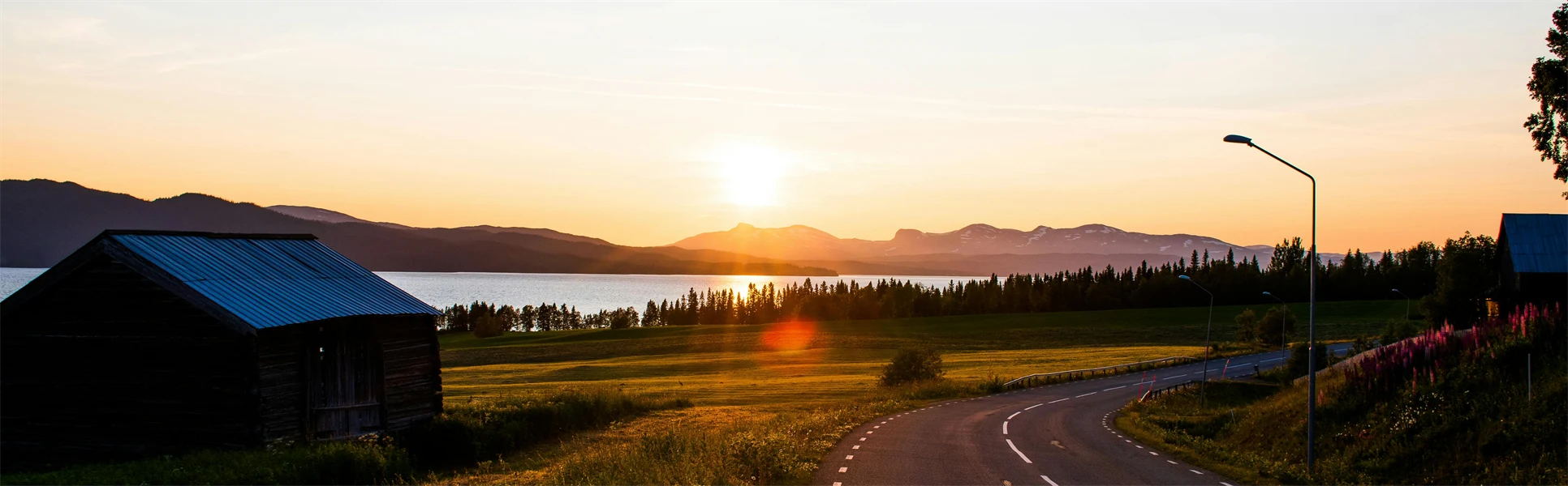 En landsväg med en lada i soluppgång.