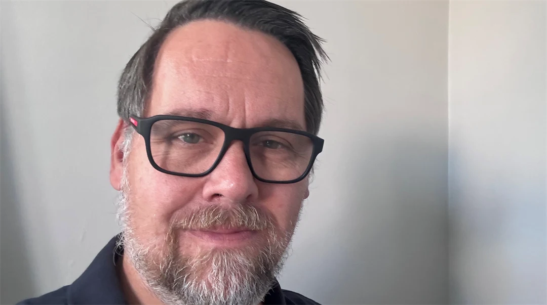 Porträttfoto av en man med brunt hår och mörka glasögon