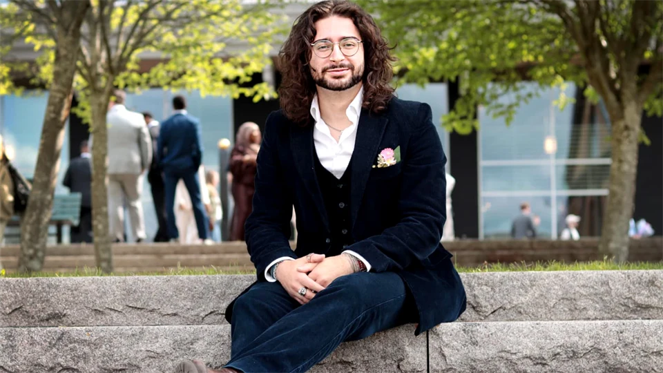 Man i kostym sitter i en trappa utomhus.