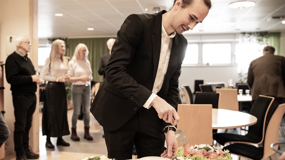 William Sjöström skär tårta efter att ha försvarat sin lic-avhandling..