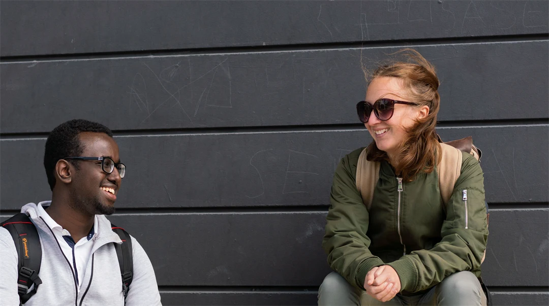 Två studenter som sitter på gul bänk.