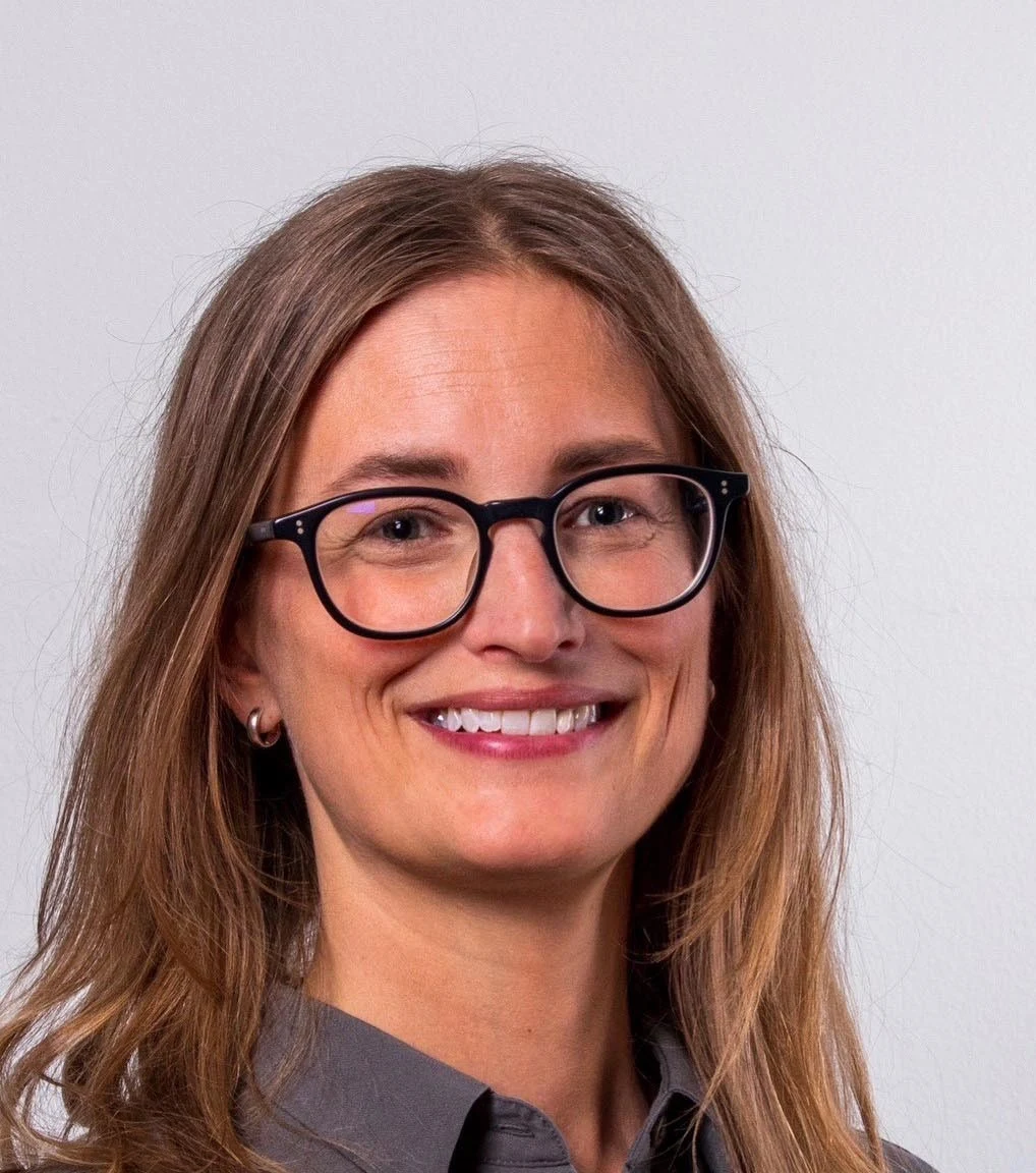 en kvinna ler och tittar in i kameran