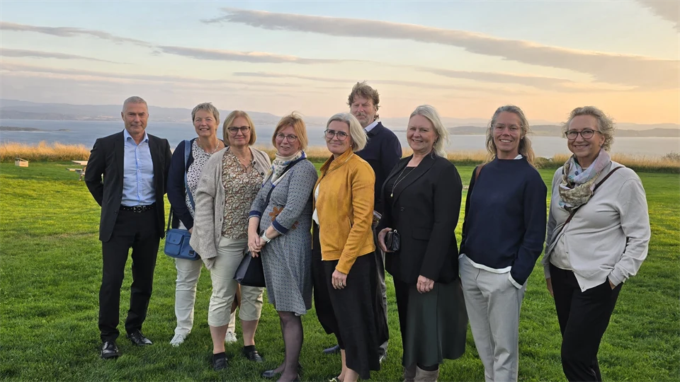 En grupp kvinnor och män står samlade på en gräsmatta