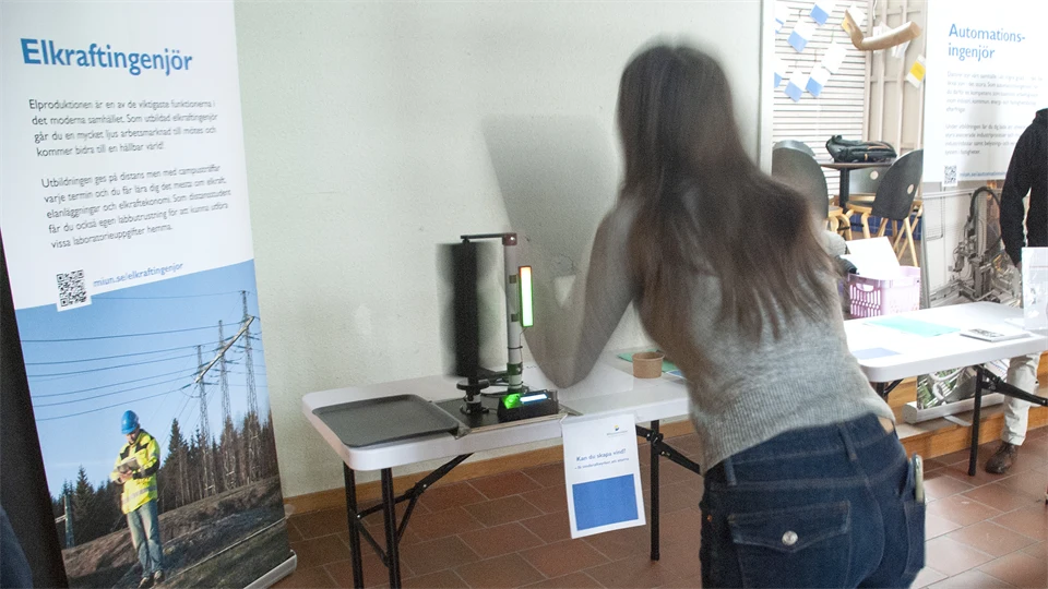 En tjej försöker skapa vind för att få ett minivindkraftverk att snurra.