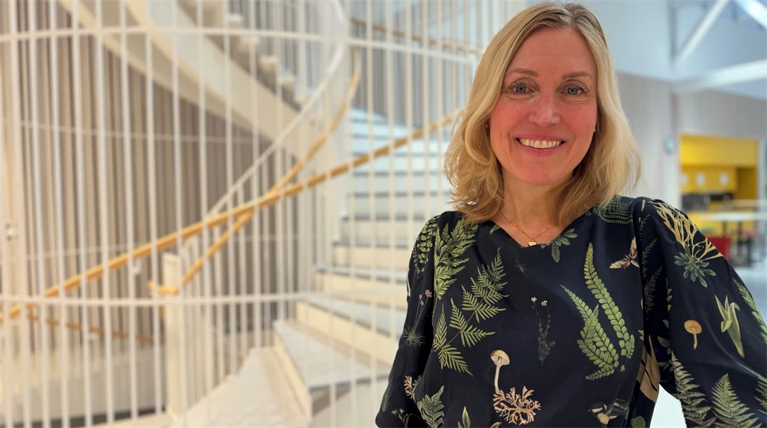 Leende kvinna i en svart klänning med gröna blommor