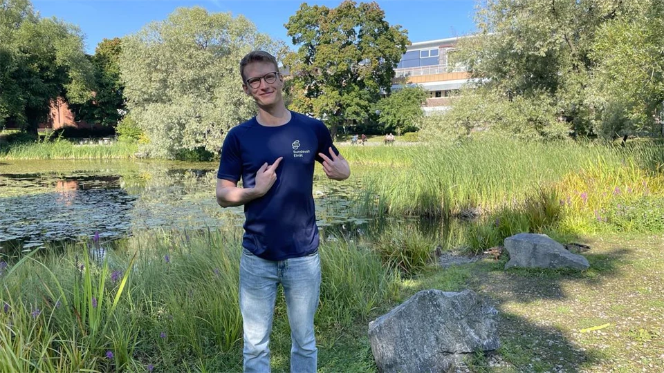 En man med blå tröja står vid vid en damm