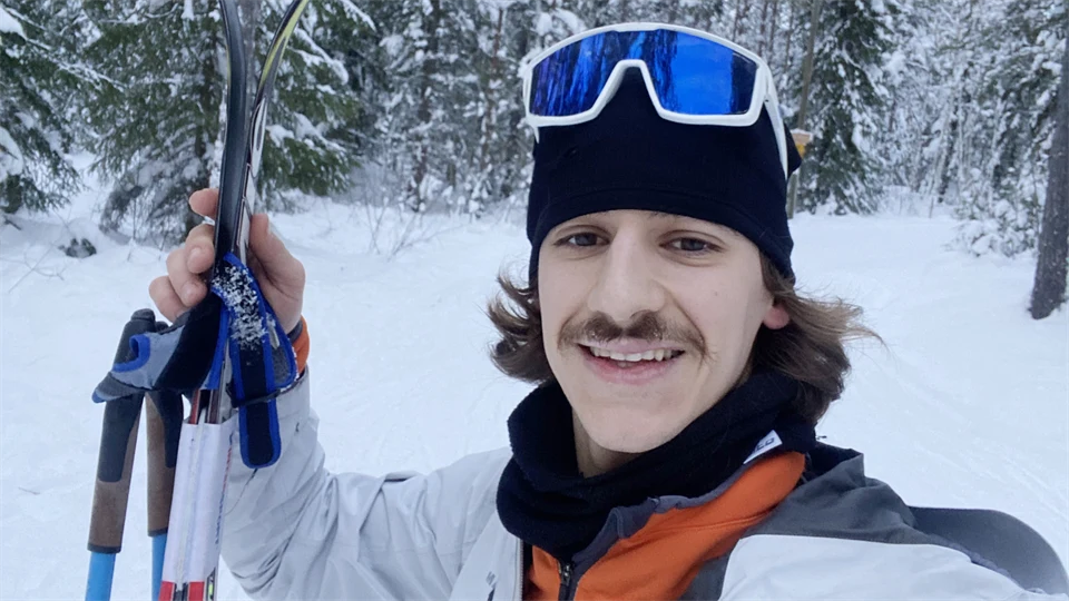 A man stands in a cross country skiing track.