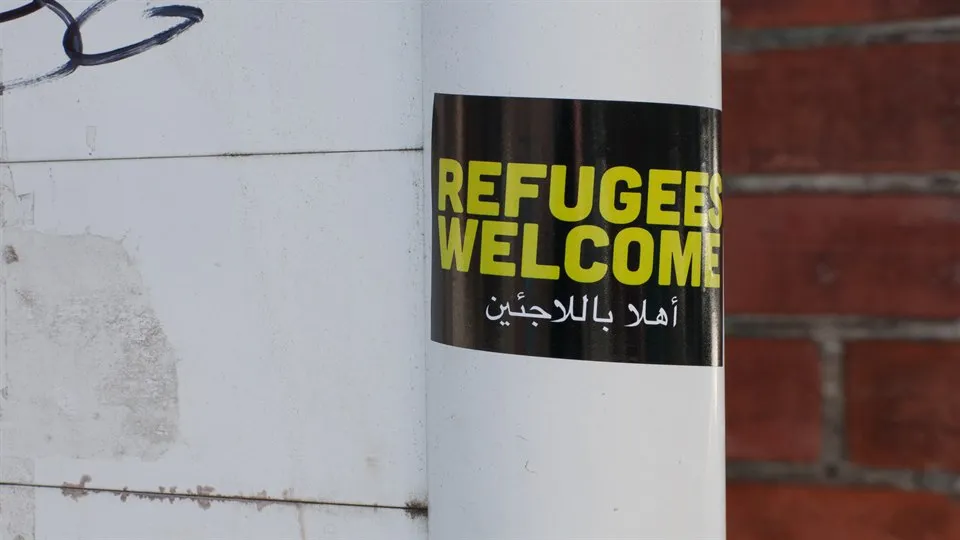 Klistermärke på stolpe Refugees welcome