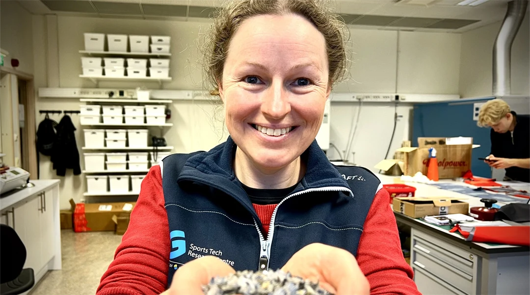 En kvinna håller fram händerna mot kameran. I händerna håller hon små platsbitar.