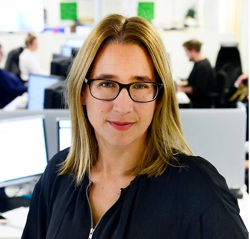 en kvinna ler och tittar in i kameran