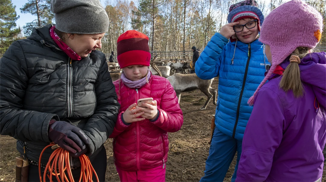 En flicka visar något på sin mobil för en kvinna.