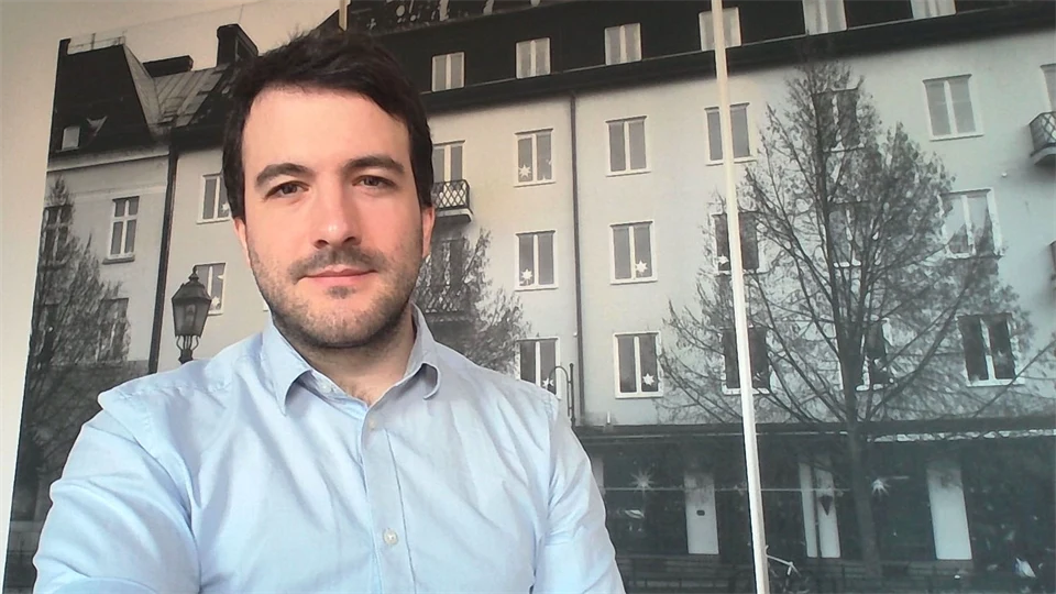  A man stands in front of a large photograph of a house facade.