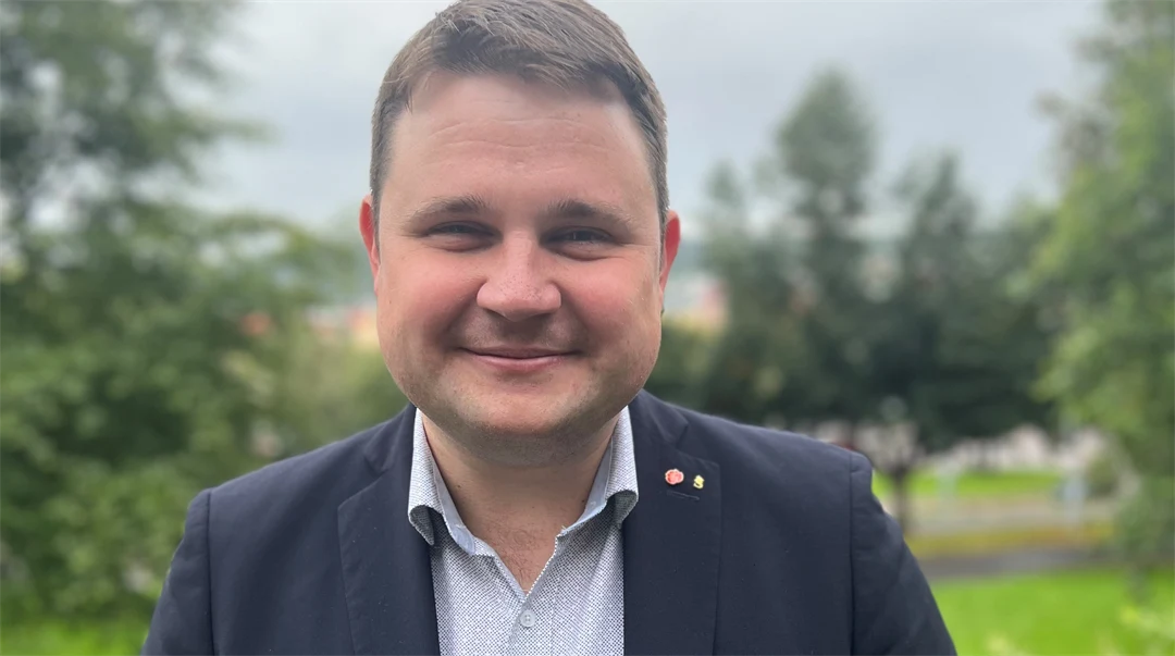 Porträttbild av leende mörkhårig man i mörk kavaj och grå skjorta