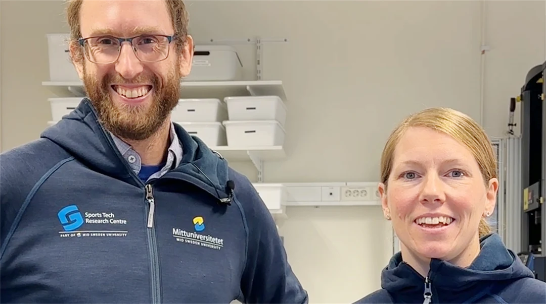 En man och kvinna, båda klädda i blått, i en labbmiljö.