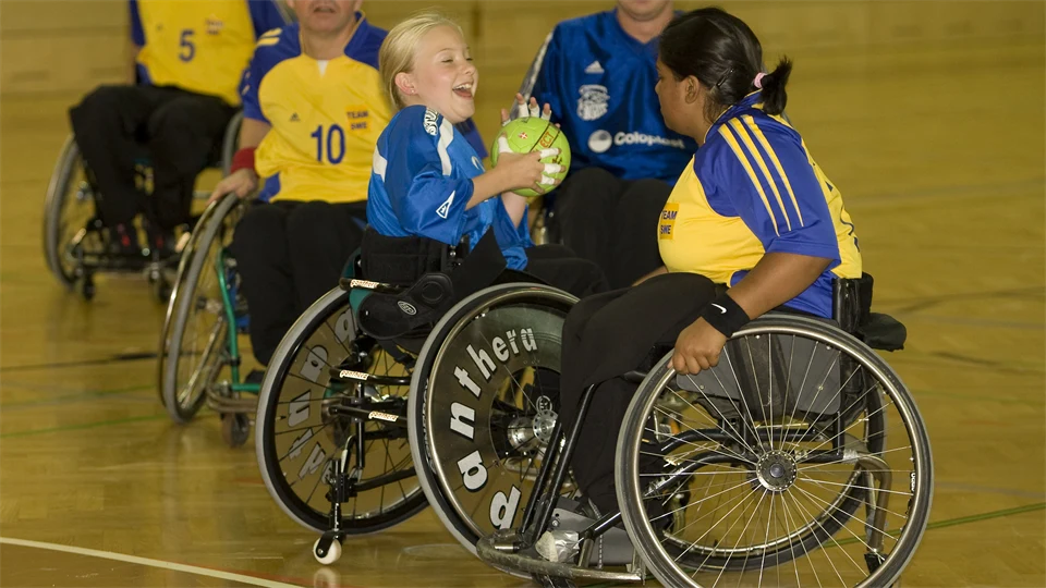 handboll parasport, 5 människor med nummerlappar  i rullstol i sporthall