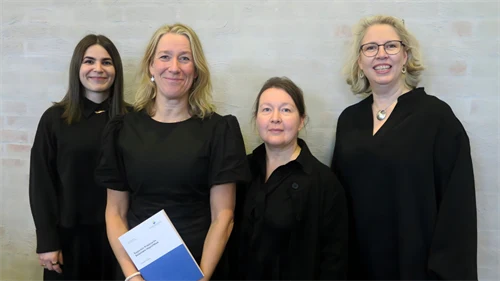 Fyra kvinnliga forskare står i en lärosal med en blombukett i famnen