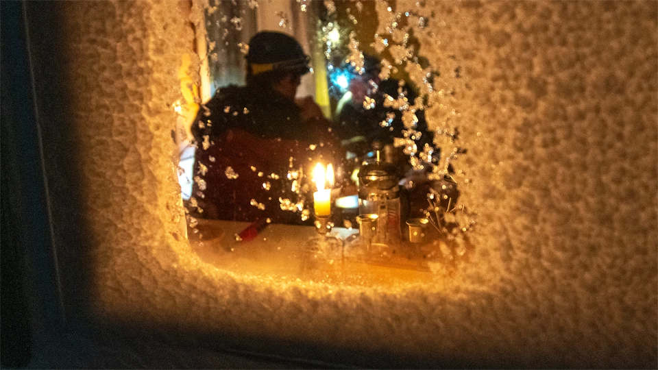 En person sitter i ljuset innanför ett igensnöat fönster.