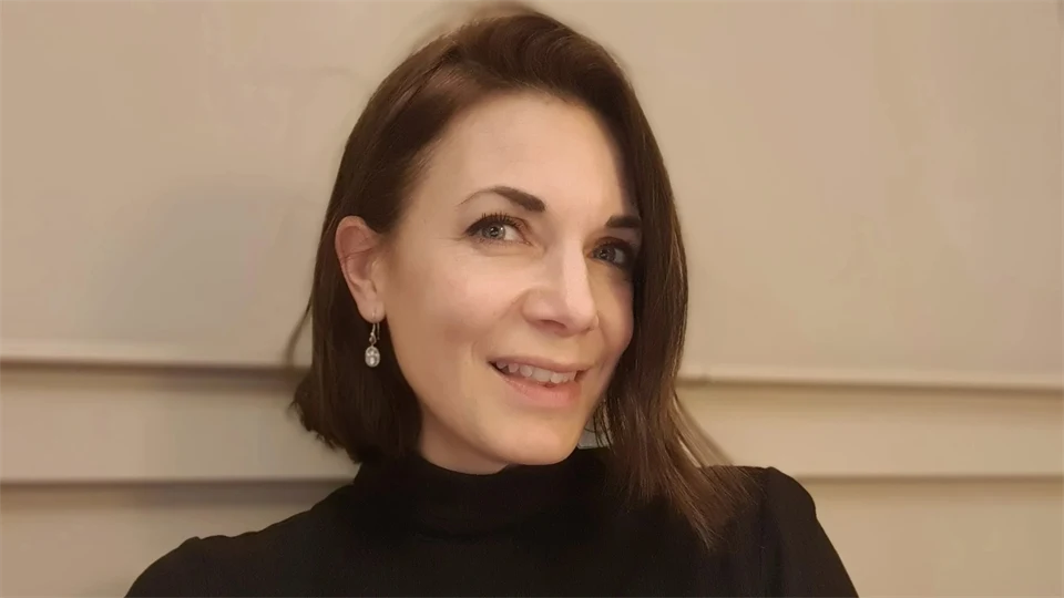 En kvinna tittar in i kameran och ler. 