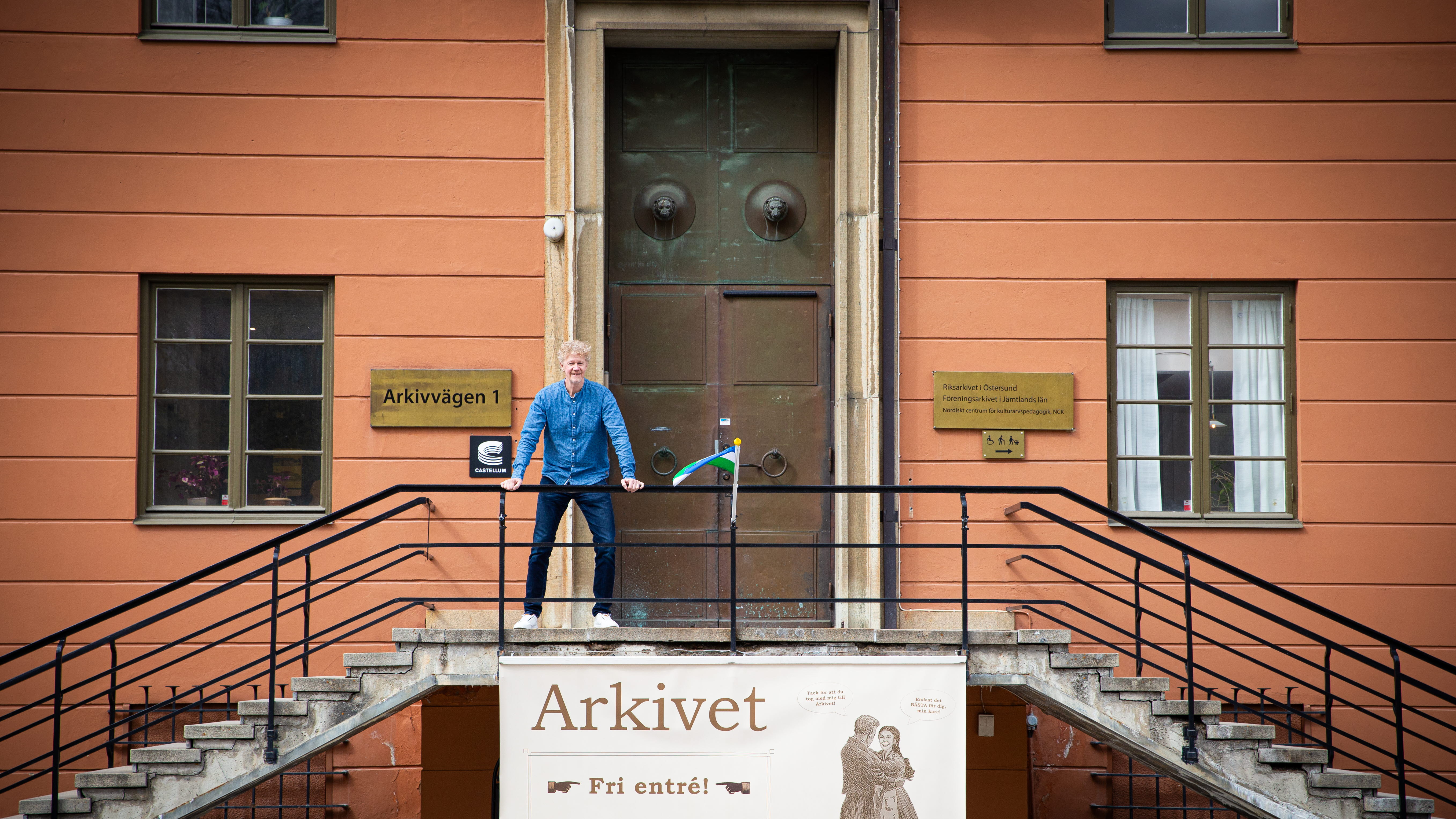 En man står utanför en stor port och håller sig i ett räcke. 