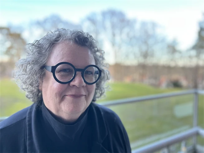 Porträttfoto av kvinna med grått hår och svarta glasögon