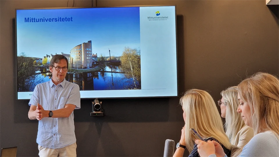 Man framför en skärm presenterar för sittande publik.