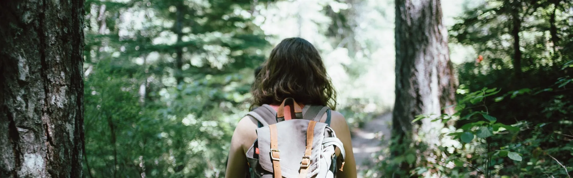 Kvinna med ryggsäck går genom skog