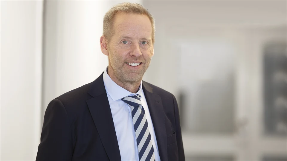 A man in a jacket in front of a white glass door