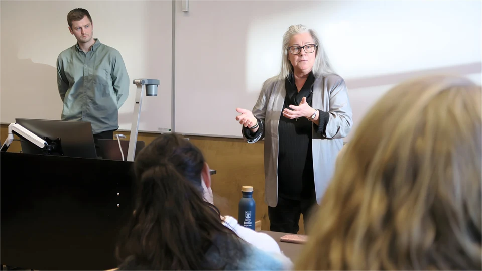 Ung man och kvinna i övre medelåldern håller en föreläsning i en lektionssal