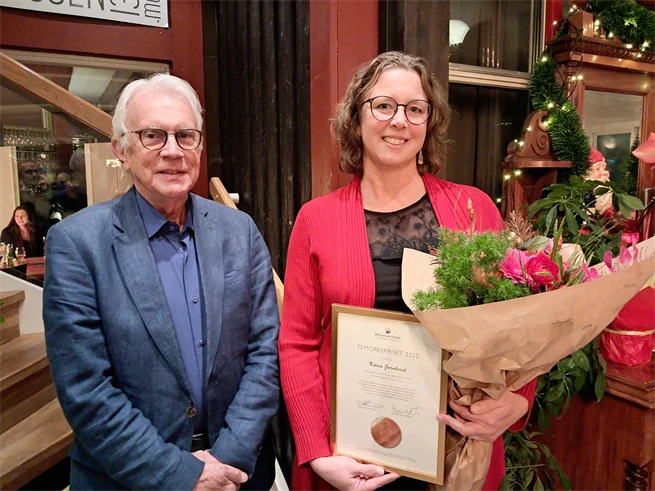 Man i blå kavaj intill kvinna i röd kavaj med diplom och blombukett i famnen