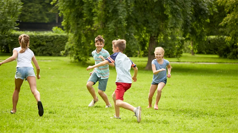 Glada barn som springer och leker på gräset.