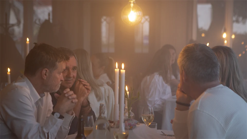 Människor runt matbord med levande ljus.