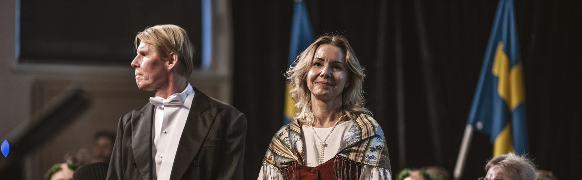 En finklädd man och en finklädd kvinna står bredvid varandra på en scen. 