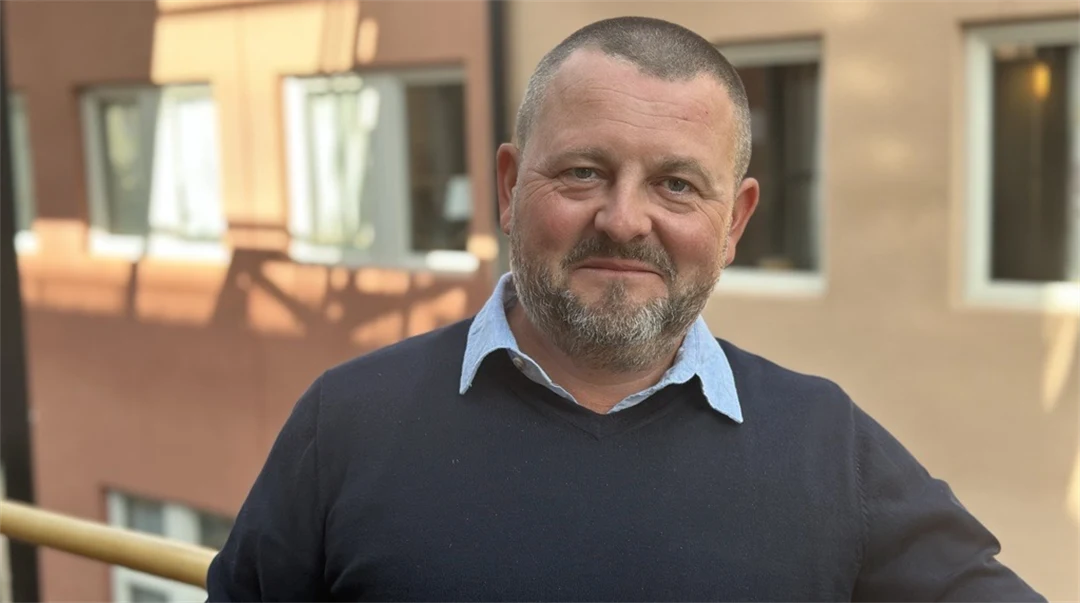 En man med snaggat mörkt hår och en mörkblå tröja