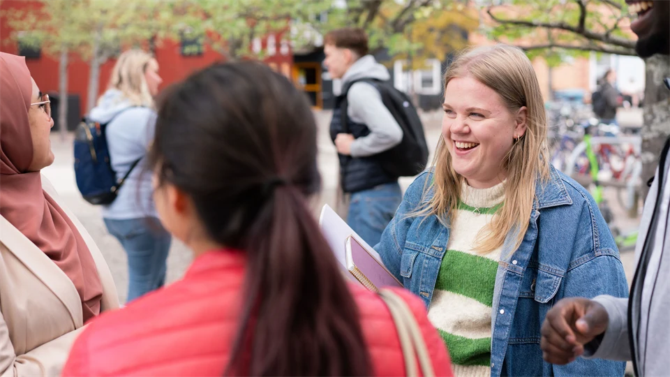 En grupp studenter som står och pratar med varandra utanför campus. 