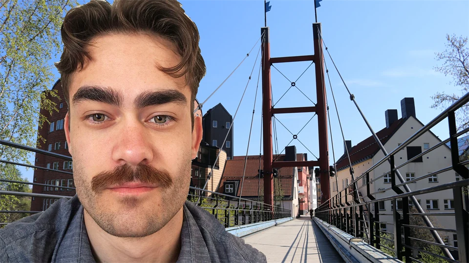 Porträtt av en man med mustasch, i bakgrunden en bro samt byggnader