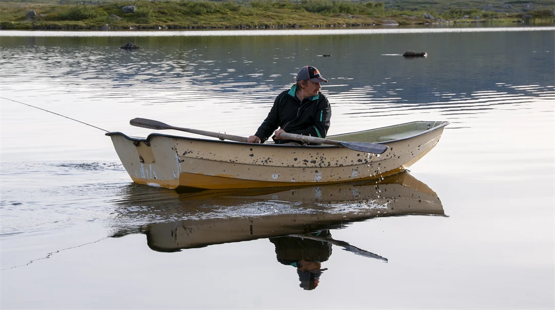 Man ror en båt i en sjö.