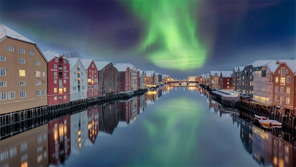 A canal with buildings on both sides. Northern lights in a dark blue sky.