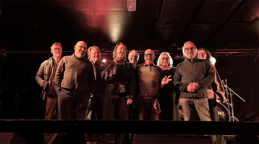 En grupp människor samlade på en scen i en mörk klubblokal