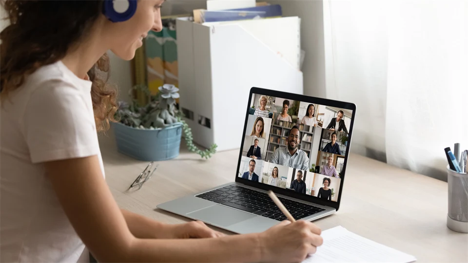 Kvinna med mörkt hår sitter framför en dator i ett digitalt möte.
