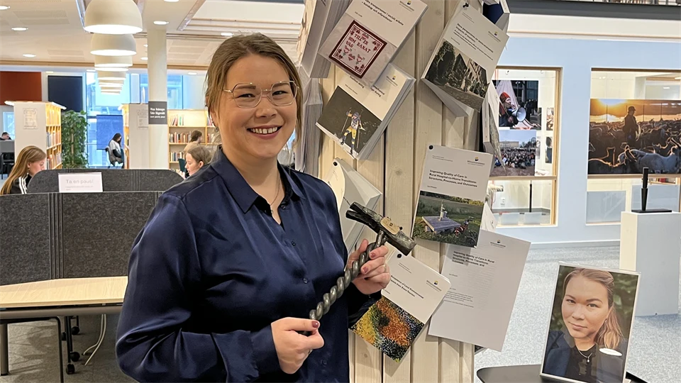 En mörkhårig kvinna med glasögon och en blå blus håller i en sirlig hammare.