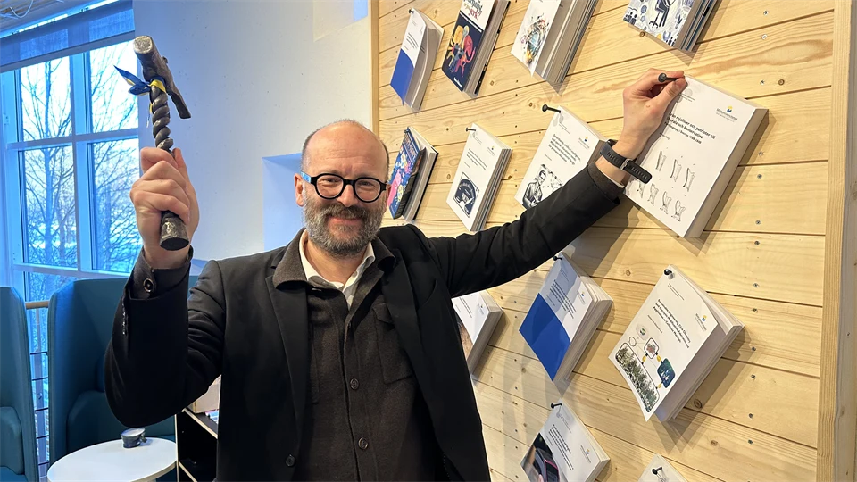 En man med en hammare spikar upp sin avhandling