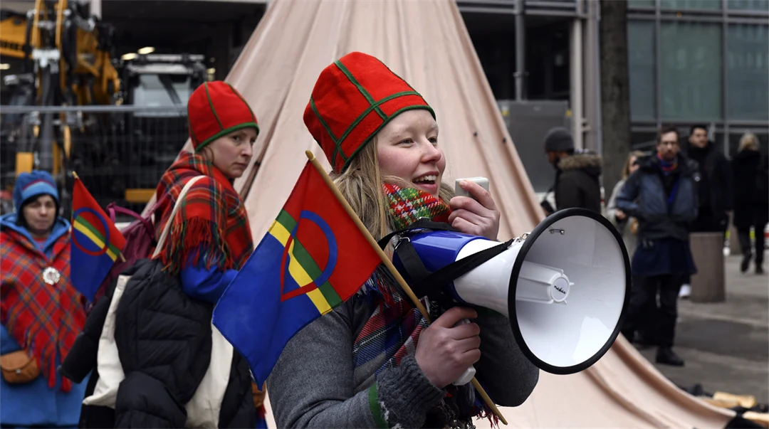 Kvinna håller en sameflagga och talar i en megafon.