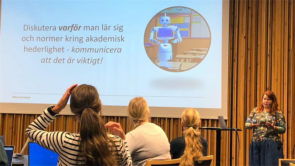 Seminariesituation med en föreläsare, publik och presentationsbild på väggen.